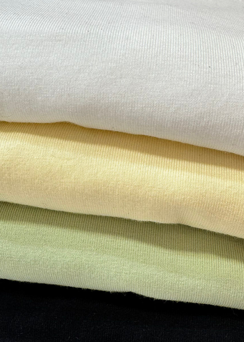 Stack of white, yellow, green and black t-shirts  