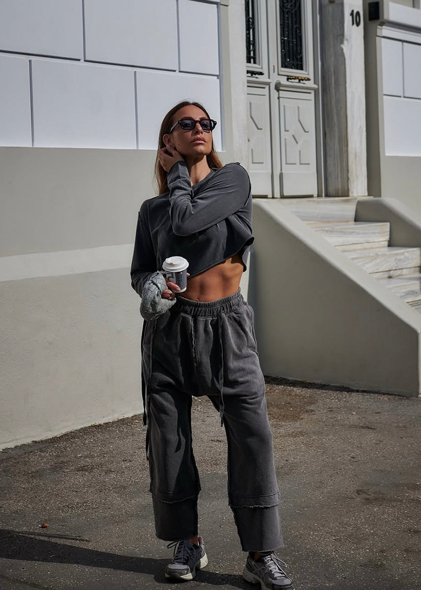 Person wearing a gray outfit holding a coffee cup in an urban setting