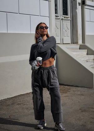 Person wearing a gray outfit holding a coffee cup in an urban setting