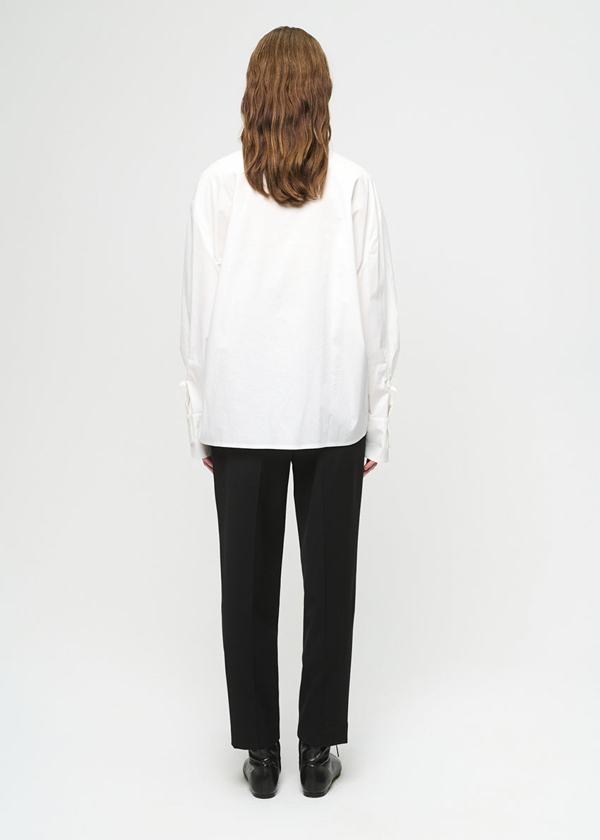 Person wearing a white blouse and black pants on a white background