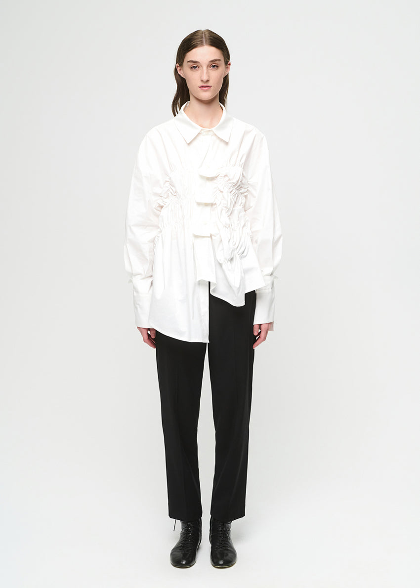 Person wearing a white blouse and black pants on a white background