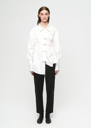 Person wearing a white blouse and black pants on a white background