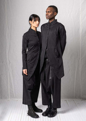 Two people wearing matching black outfits against a plain background