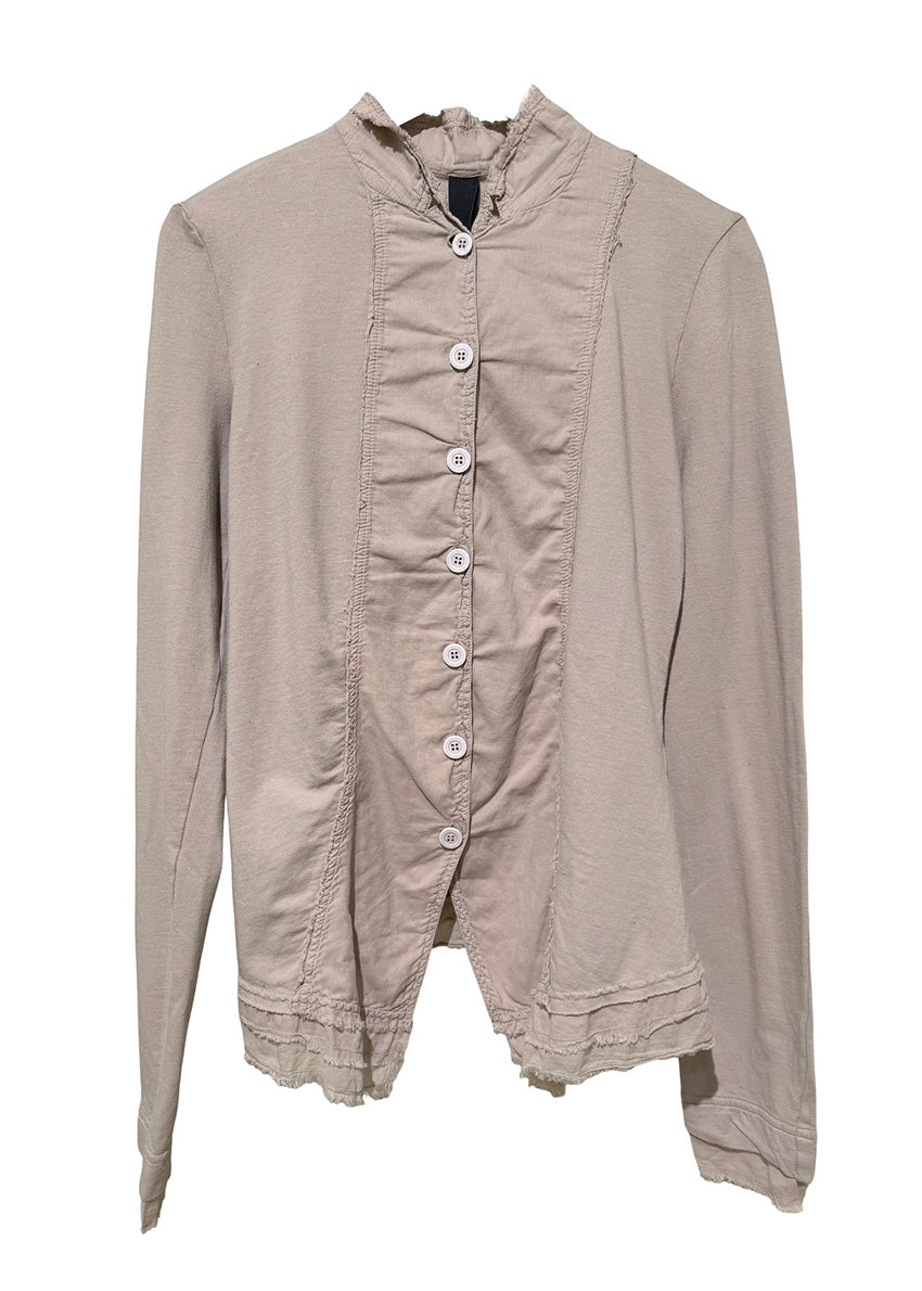 Person wearing a beige jacket and black pants standing against a white background