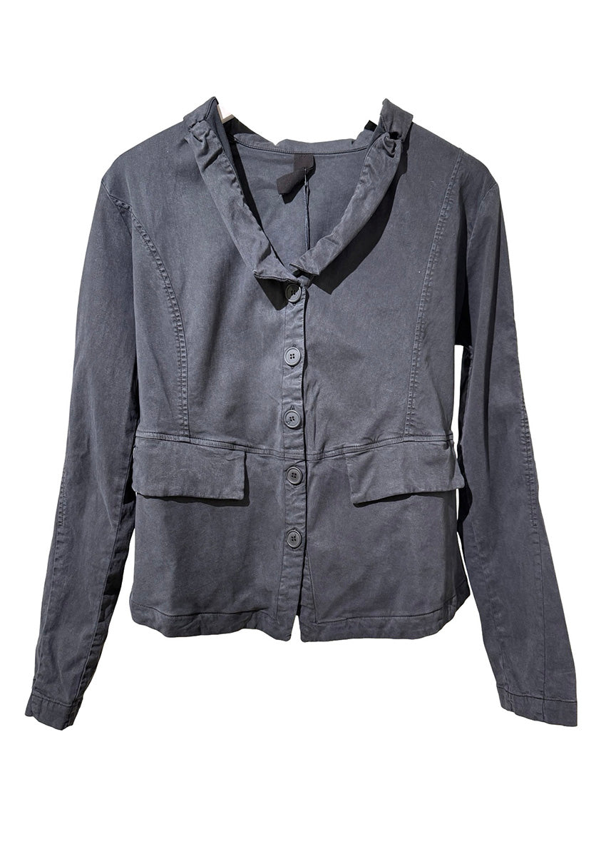 Person wearing a dark gray jacket, black gloves, and blue jeans on a gray background