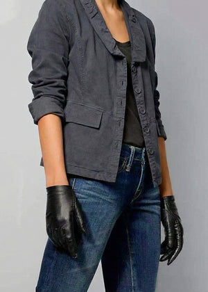 Person wearing a dark gray jacket, black gloves, and blue jeans on a gray background