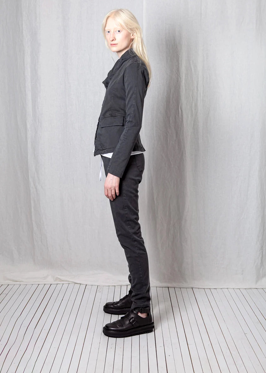 Person wearing a dark gray suit standing against a plain white background