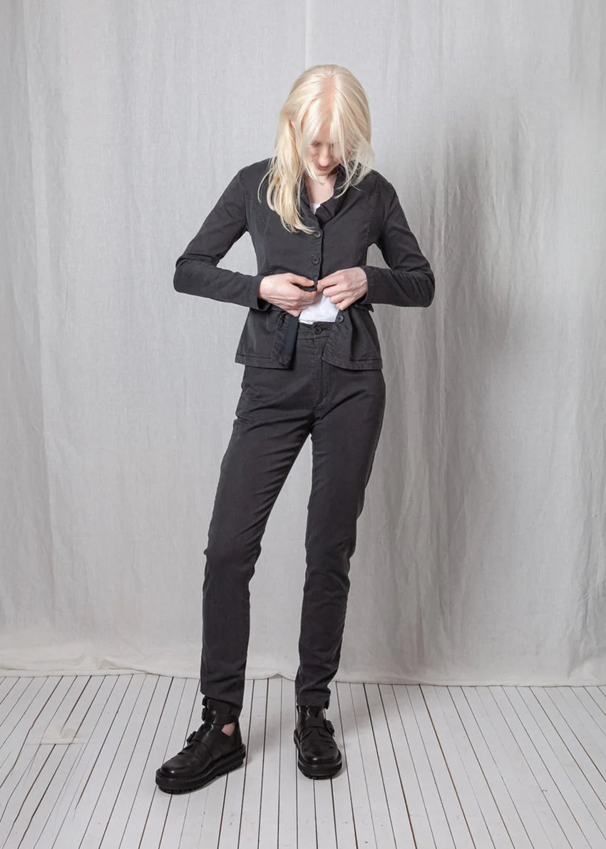 Person wearing a black suit standing against a plain white background