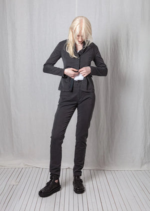 Person wearing a black suit standing against a plain white background