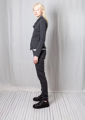 Person wearing a dark gray suit standing against a plain white background
