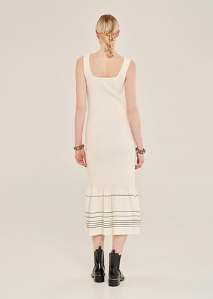 Woman wearing a white dress with black stripes on a plain background