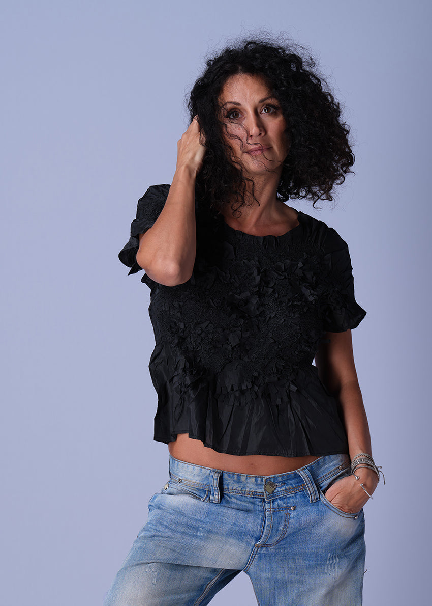 Black top with textured floral design, elasticated waist, and short sleeves.