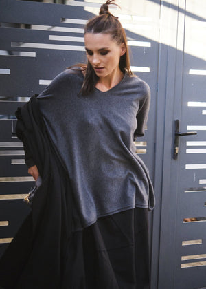 A person wearing a dim grey sweater with black pants