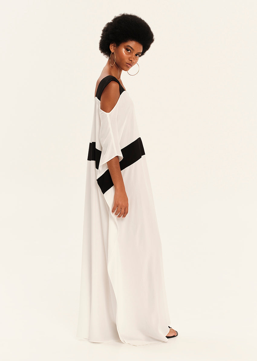 Woman wearing a white dress with black accents on a plain background