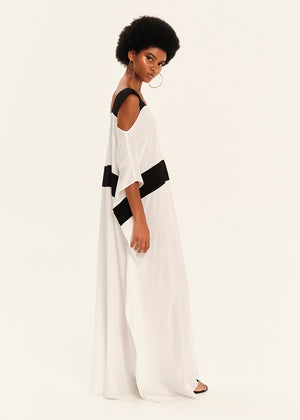 Woman wearing a white dress with black accents on a plain background
