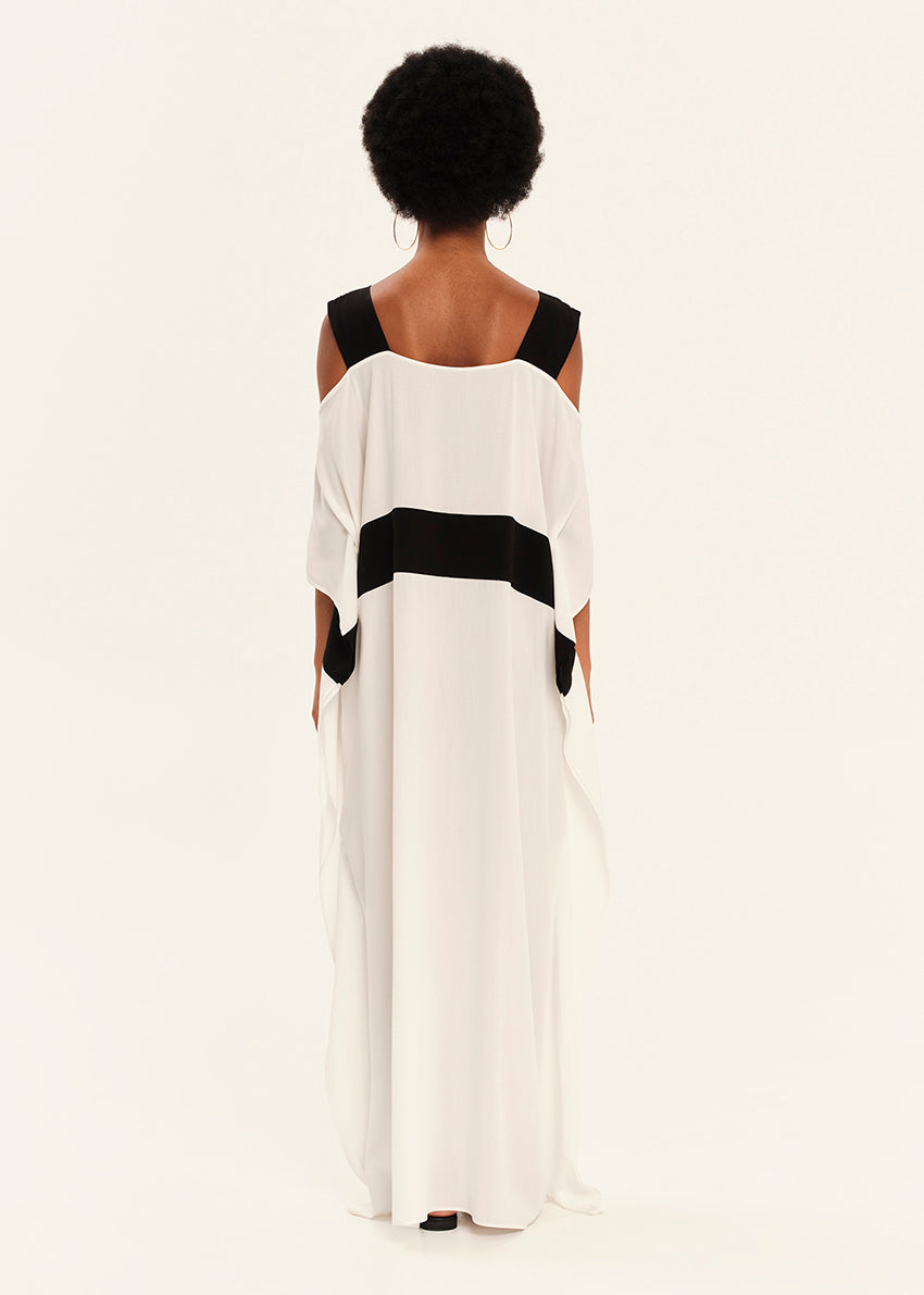 Woman wearing a white dress with black accents on a plain background