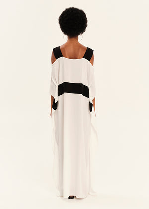 Woman wearing a white dress with black accents on a plain background