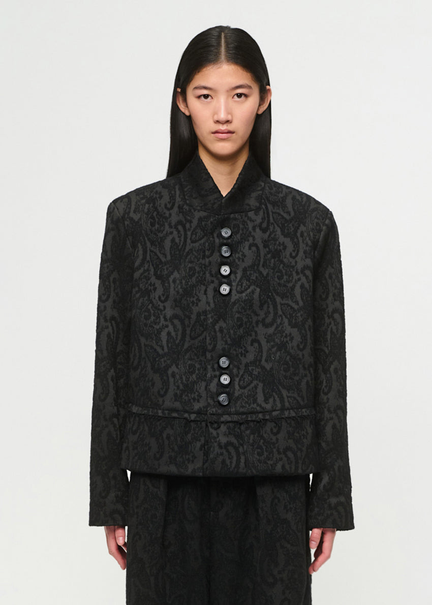 Person wearing a black patterned jacket on a white background