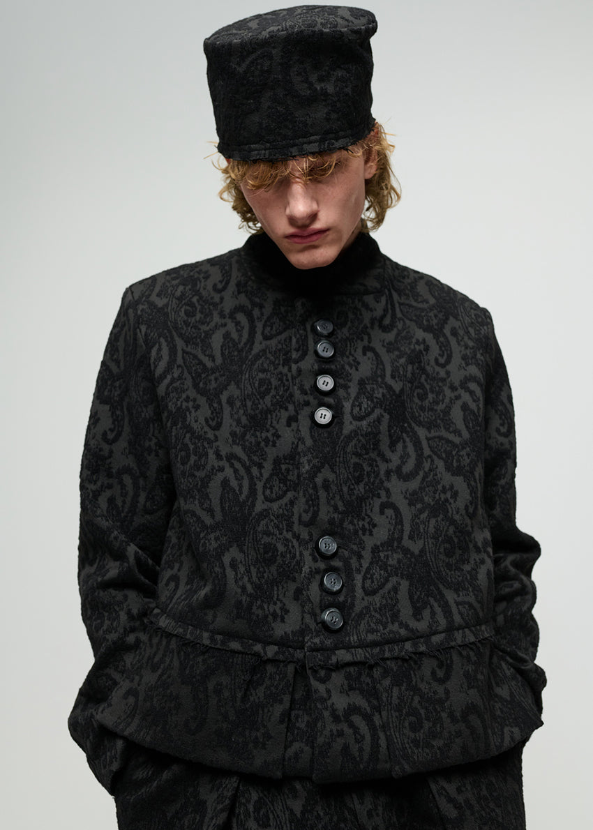 Person wearing a black patterned jacket on a white background