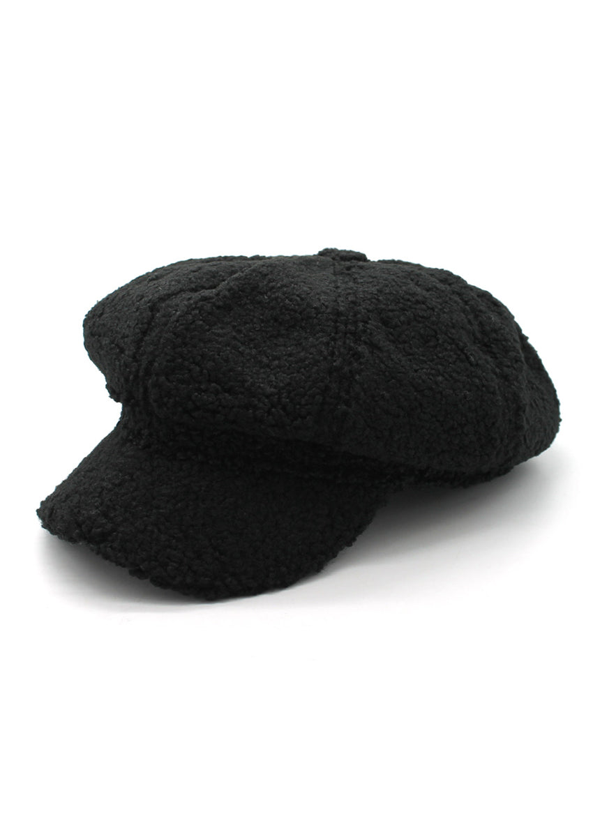 A black faux fur beret hat on a plain background.