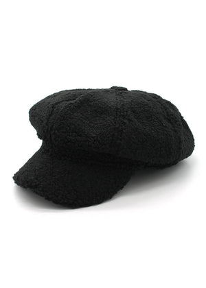 A black faux fur beret hat on a plain background.