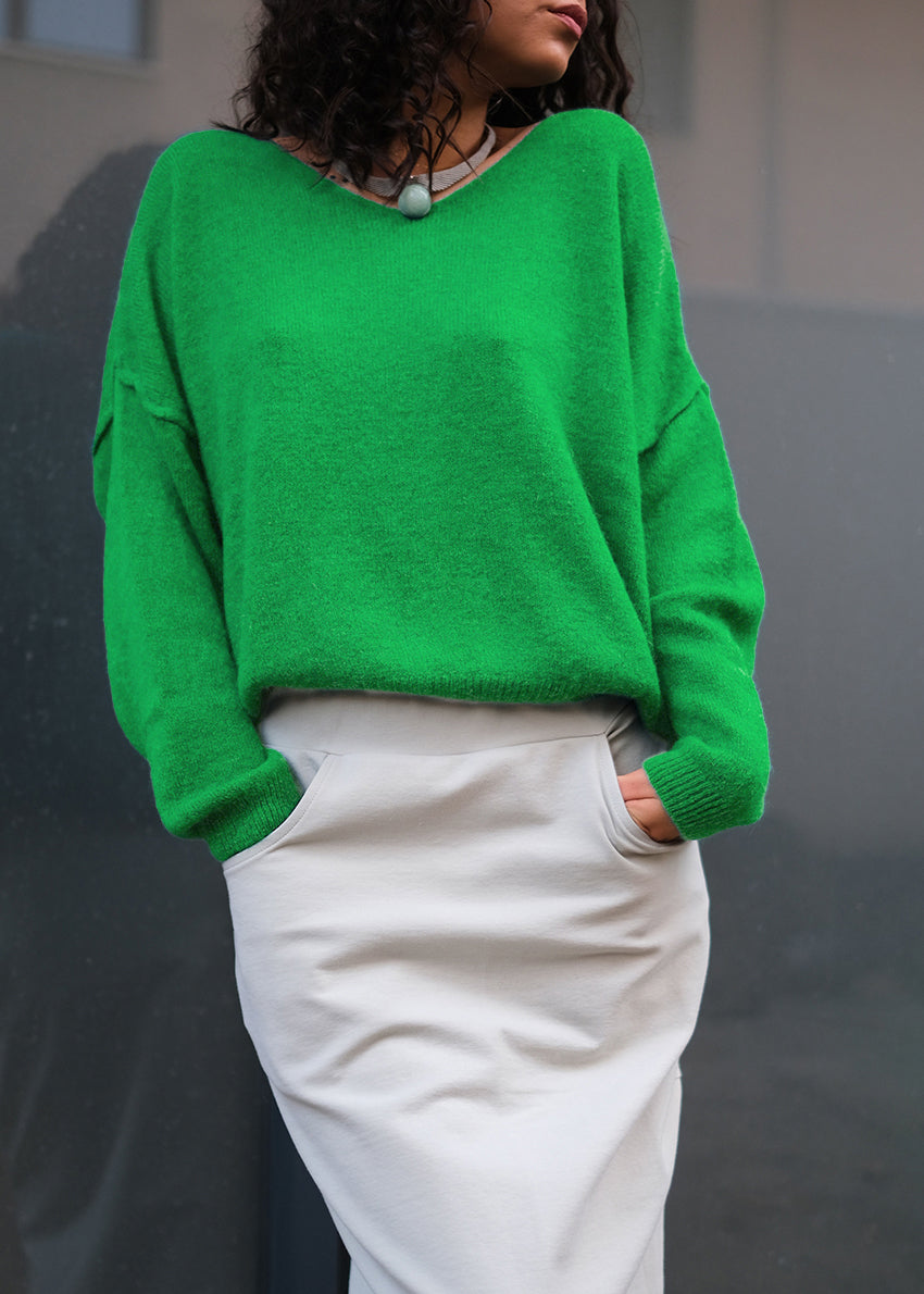 A green, loose-fitting, long-sleeved sweater with a deep V neckline.