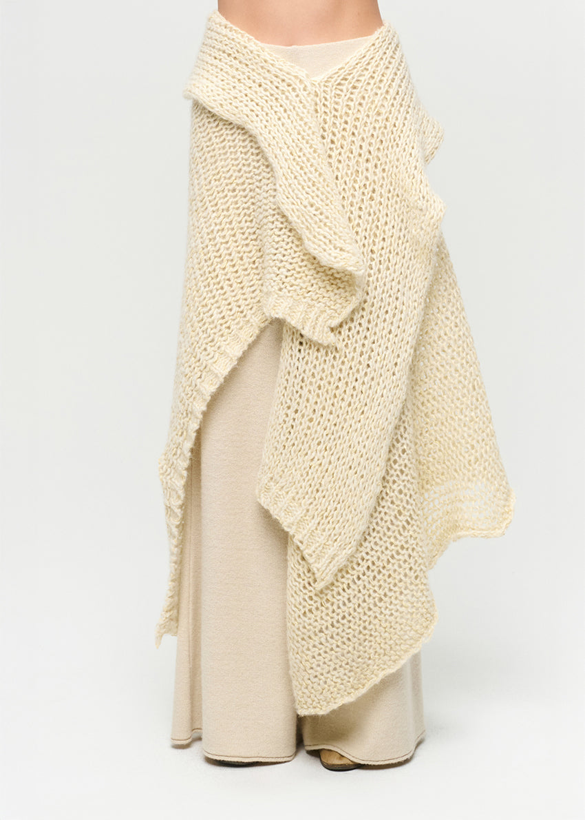 Beige knitted shawl draped over a plain background