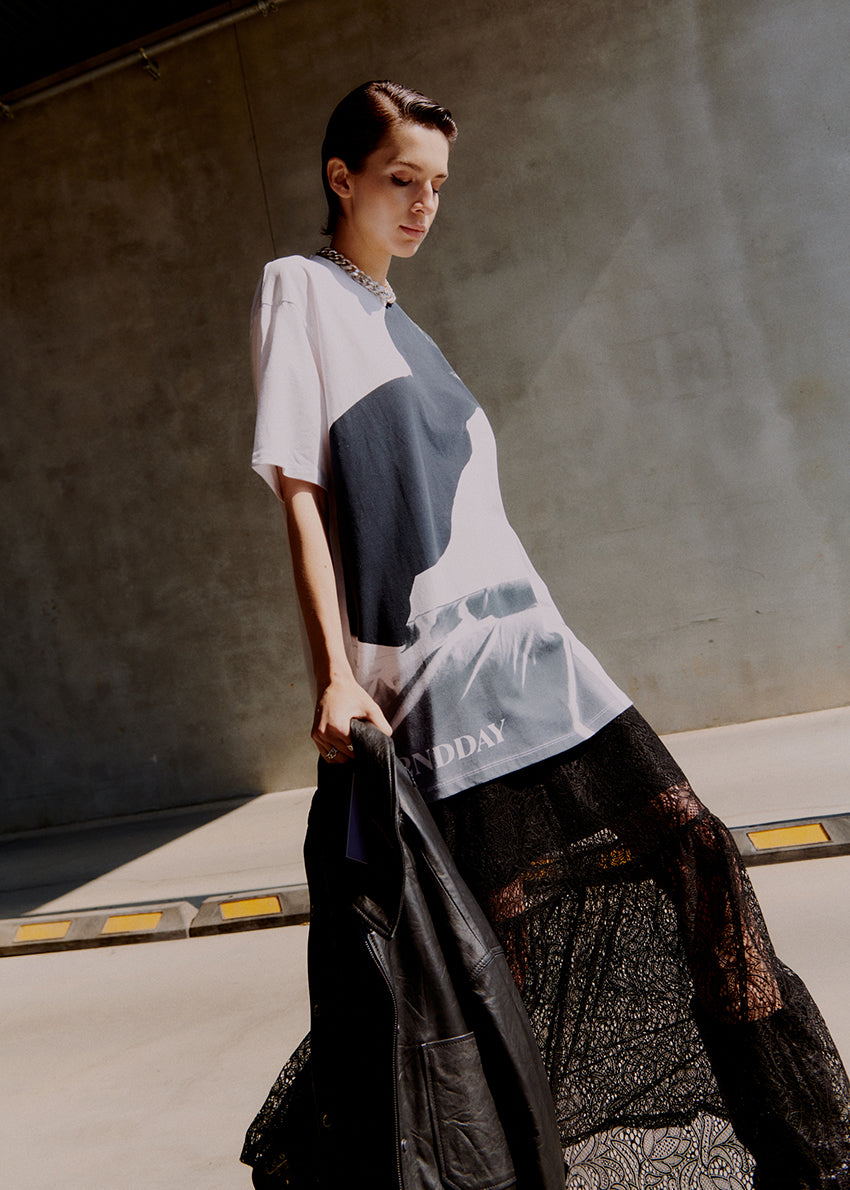 Model wearing a white t-shirt with a black graphic design on a plain background