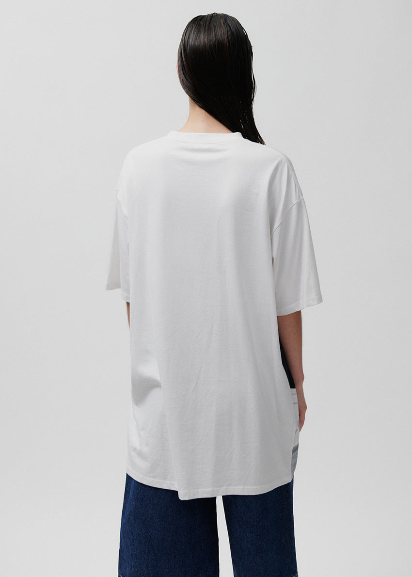 Person wearing a white oversized t-shirt on a plain background