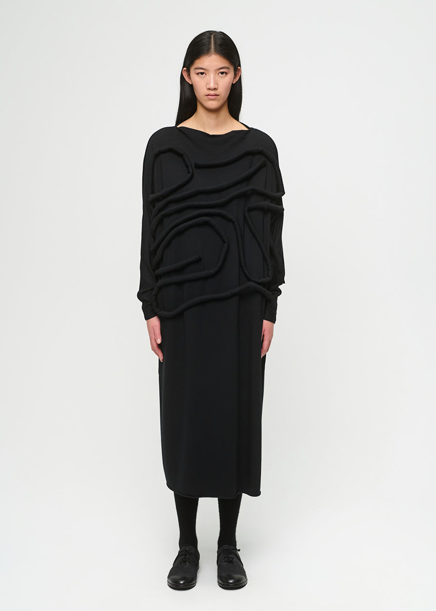 Person wearing a black, layered dress on a white background