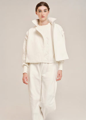 Person wearing a white outfit with a jacket and pants on a plain background