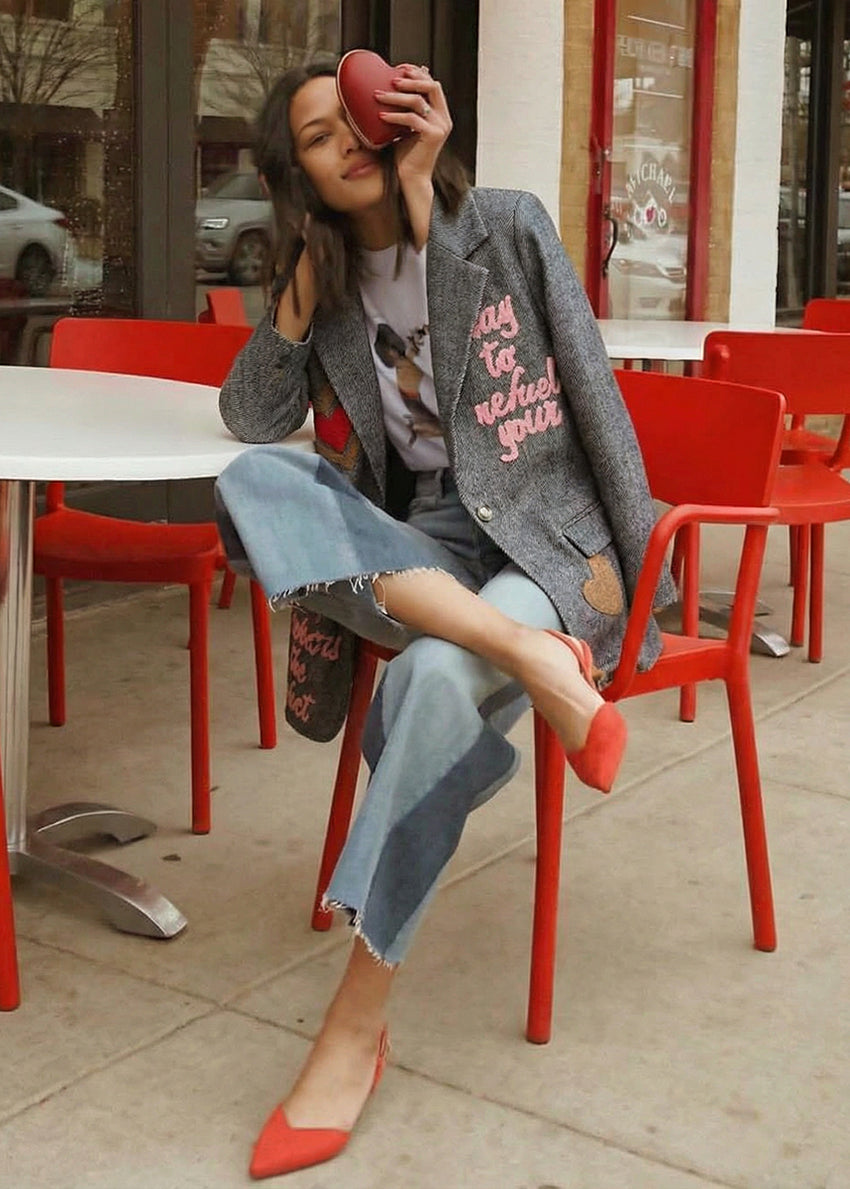 Woman sitting at a red outdoor table with a blurred city street background