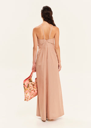 Woman wearing a beige jumpsuit holding a floral bag on a white background