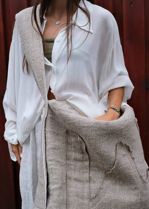 Person wearing a white shirt and beige bag with a red background