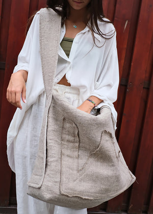 Person holding a beige tote bag against a red wooden background