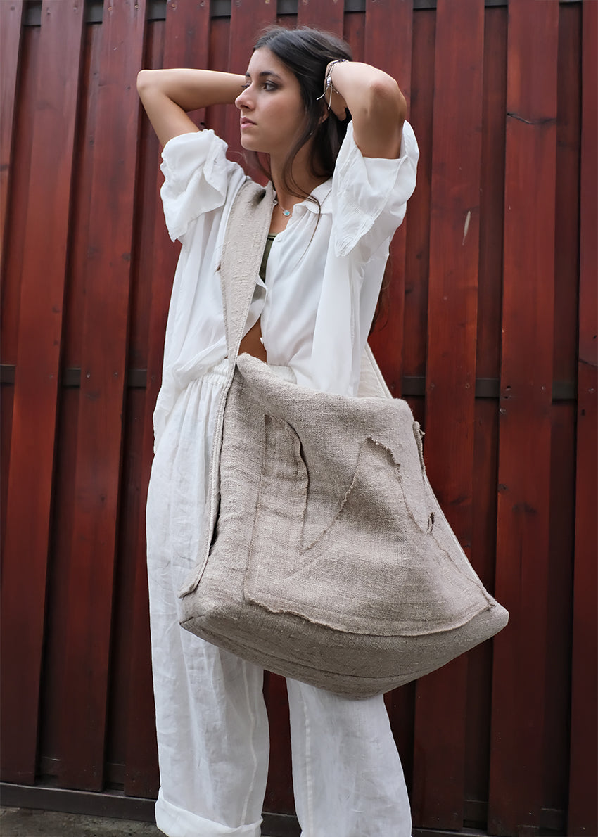 Woman holding a beige bag against a red wooden background