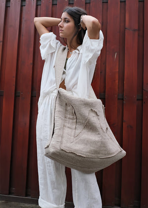 Woman holding a beige bag against a red wooden background