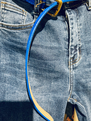 Close-up of blue jeans with a blue belt and gold buckle.