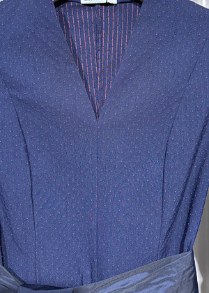 A dark blue cotton dress with textured small dots and stripes, featuring a V neckline, 3/4 sleeves with slits for adjustment, and pockets.