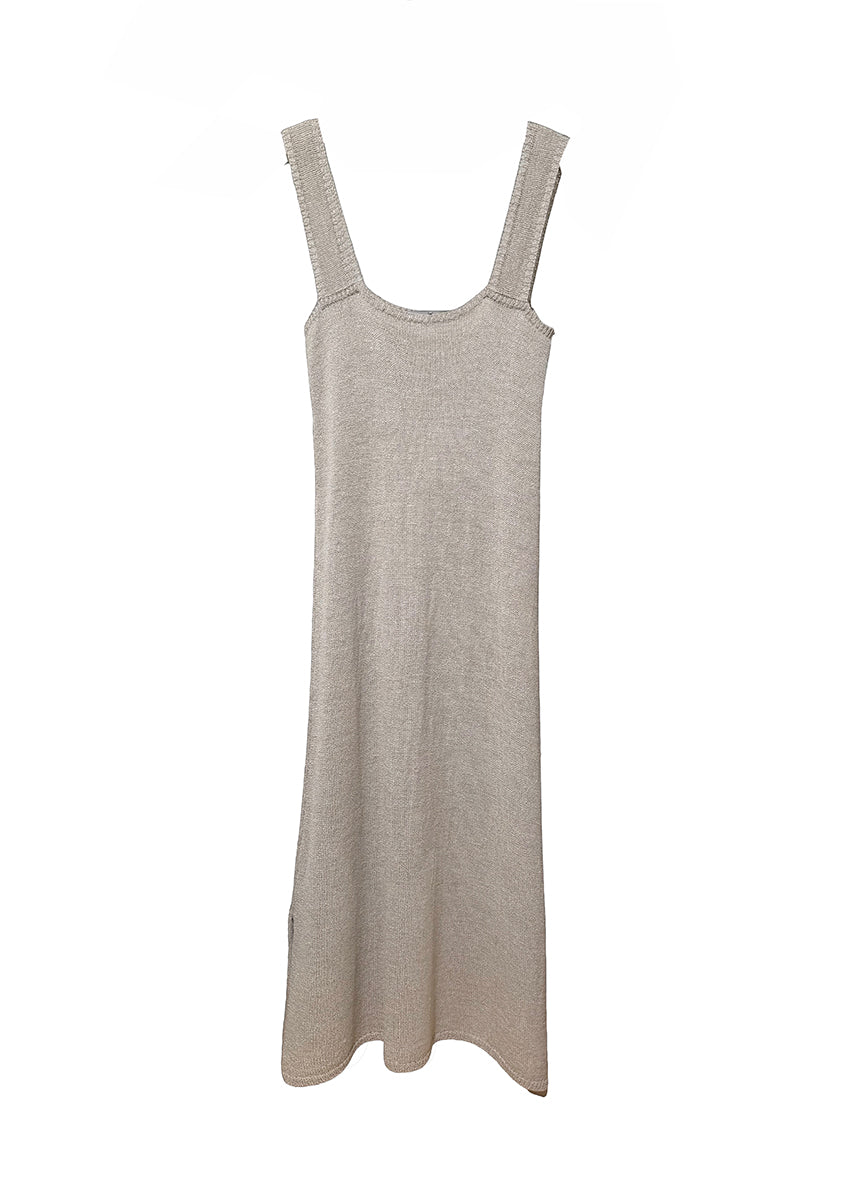 Woman wearing a beige sleeveless dress holding a gray towel against a white background
