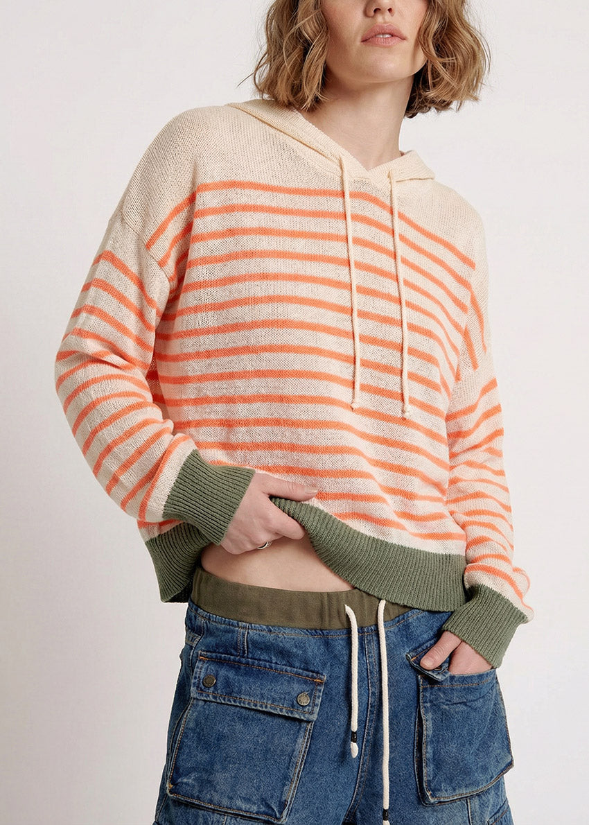 Person wearing a striped hoodie with orange and beige colors on a plain background