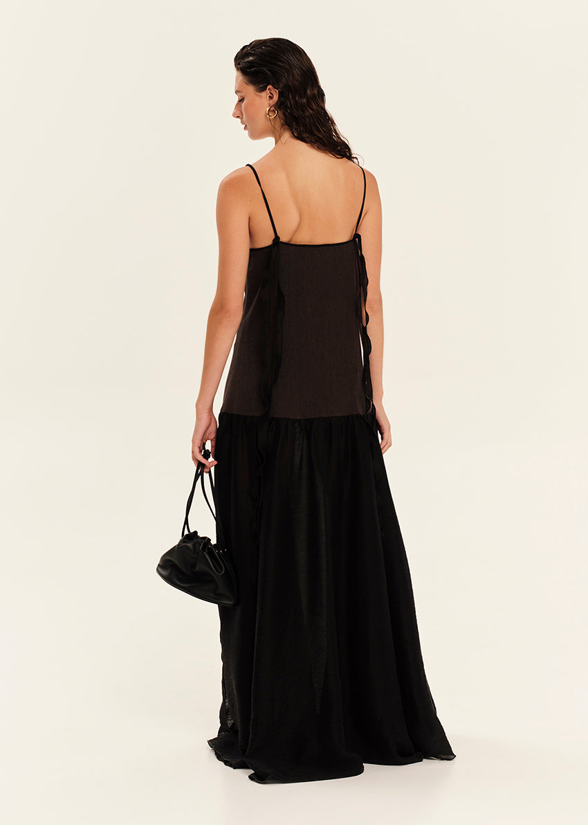 Woman wearing a black dress holding a black handbag on a white background