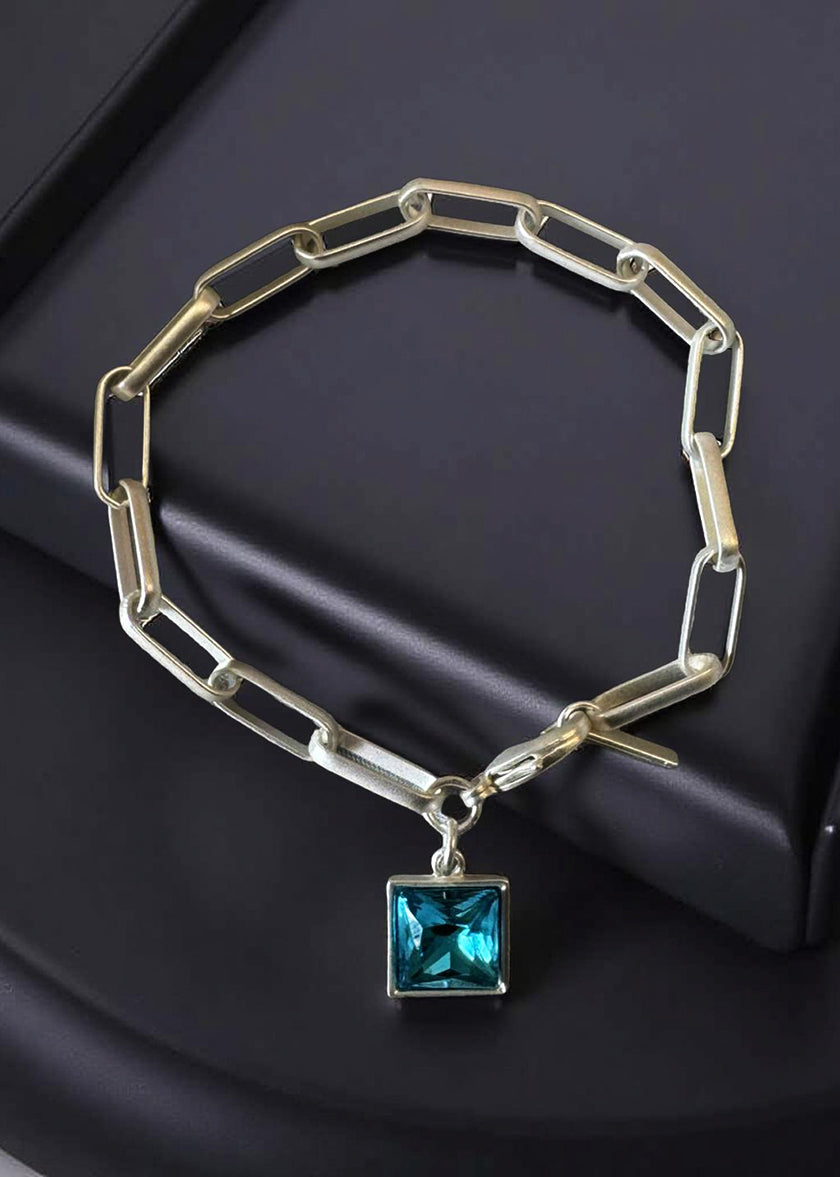 Silver bracelet with a blue gemstone pendant on a dark surface