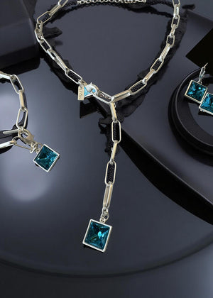 The centerpiece is a striking, square-cut blue gemstone pendant that catches the light beautifully, adding a pop of vibrant color and sophistication to any look