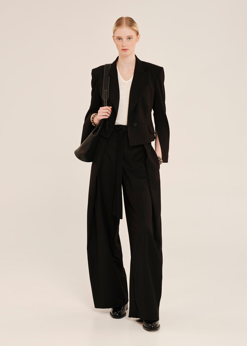 Woman wearing a black suit with a white shirt on a beige background