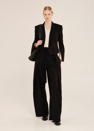 Woman wearing a black suit with a white shirt on a beige background