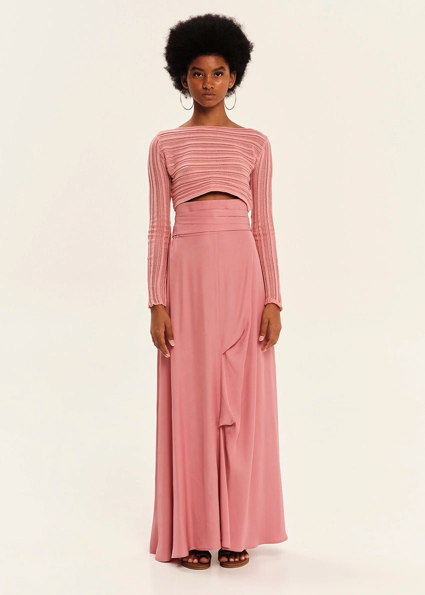 Woman wearing a pink long-sleeve top and pink skirt on a white background