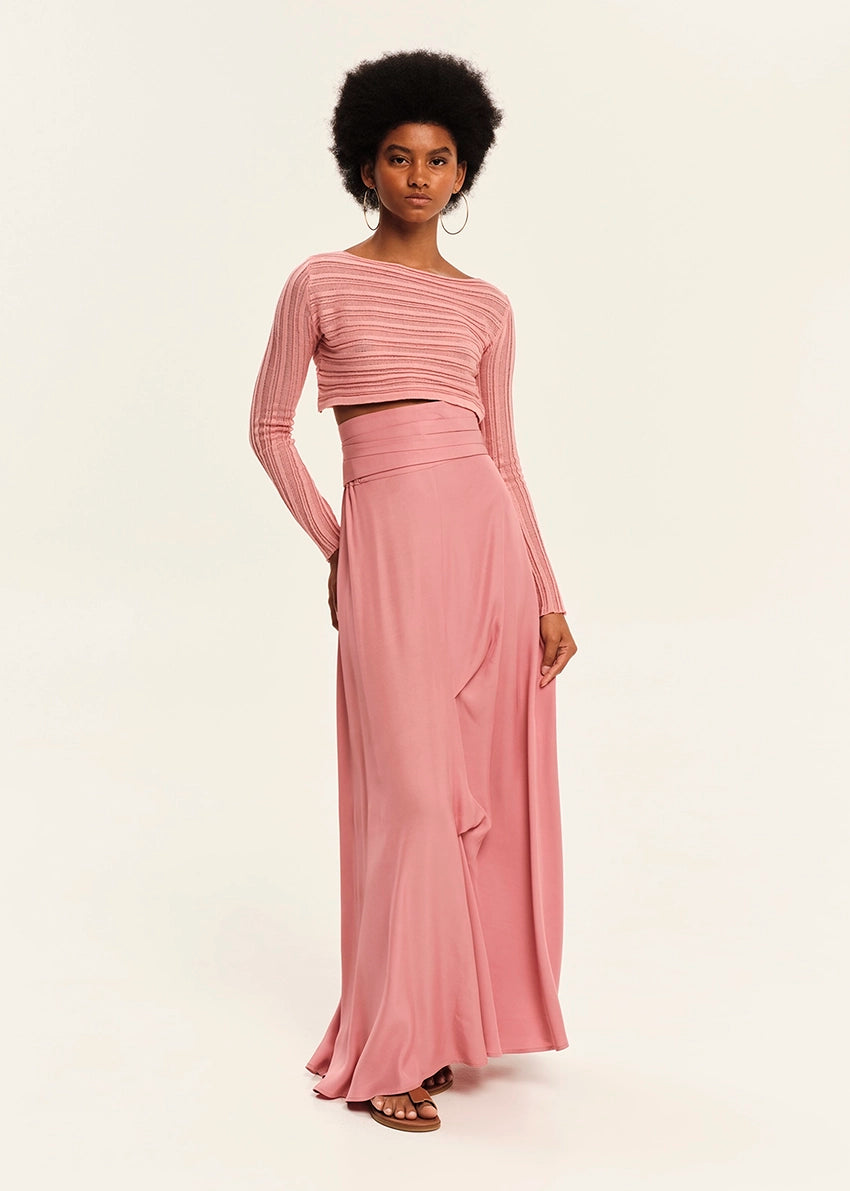 Woman wearing a pink long-sleeve top and pink skirt on a white background