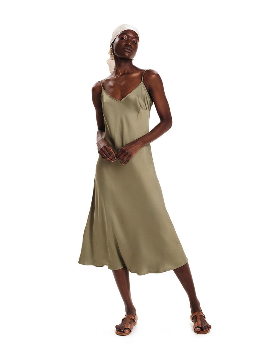 A model wearing a midi length sleeveless green dress with adjustable shoulder straps.