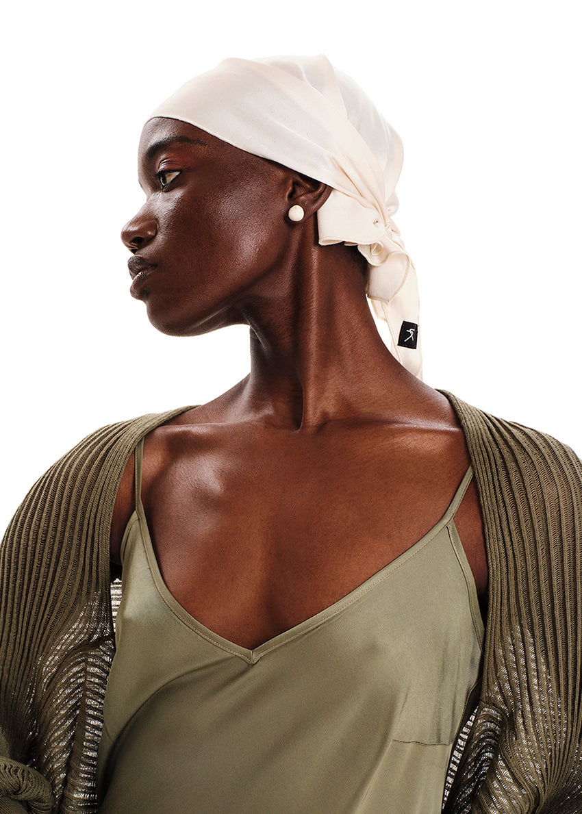 A model wearing a midi length sleeveless green dress with adjustable shoulder straps.